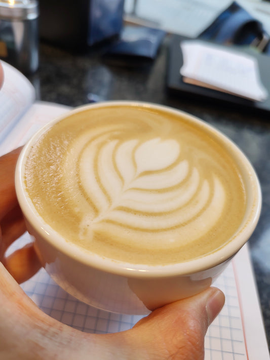 Cappuccino hold in the hand above a notebook for writing down thoughts. 