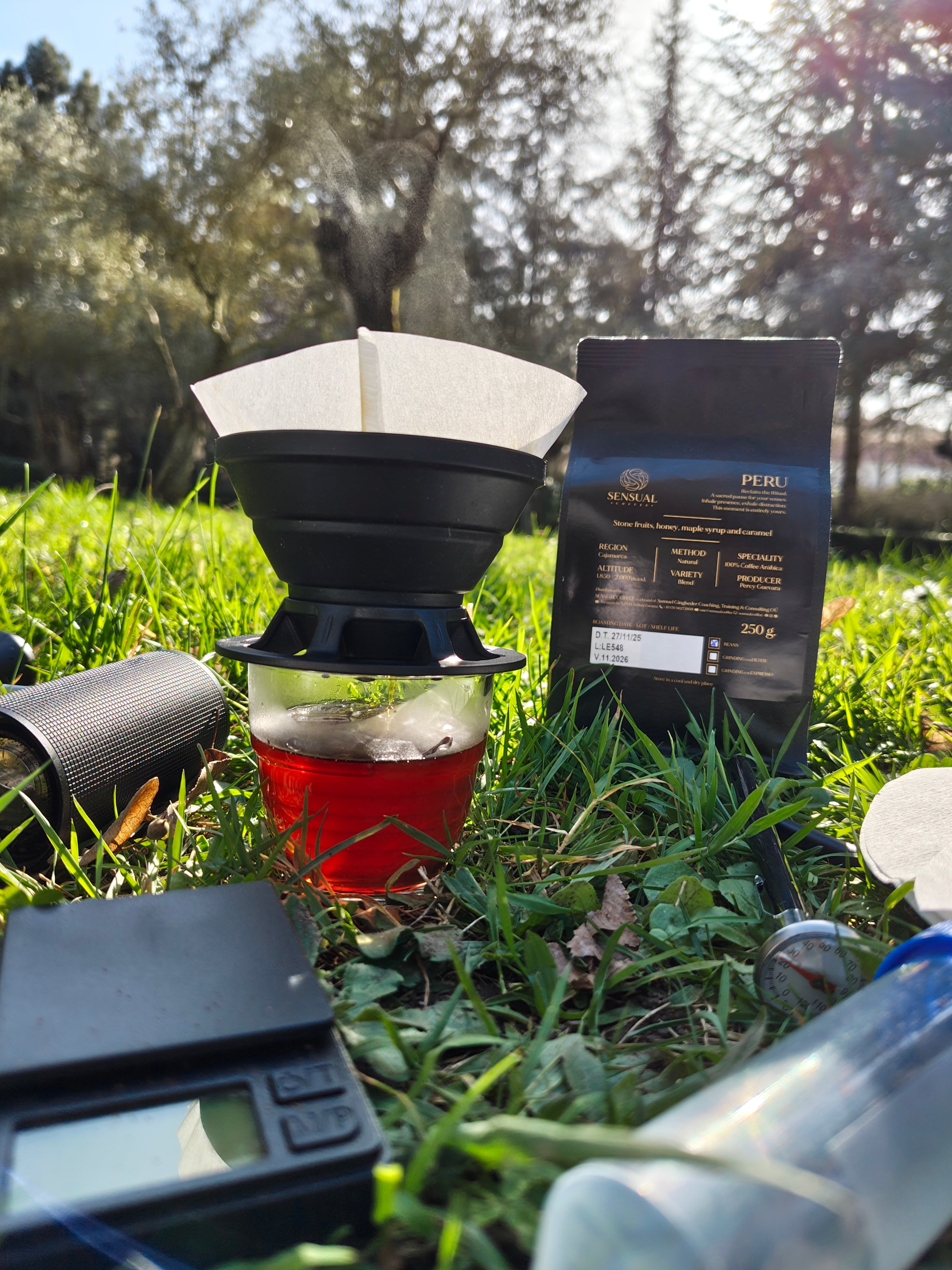 Coffee brewing setup with a filter, coffee grounds, and a measuring device outdoors.